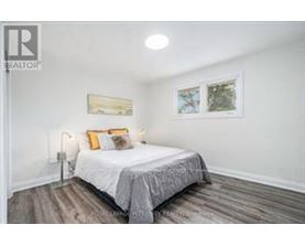 A bedroom with a bed, pillows, and pictures on the wall.