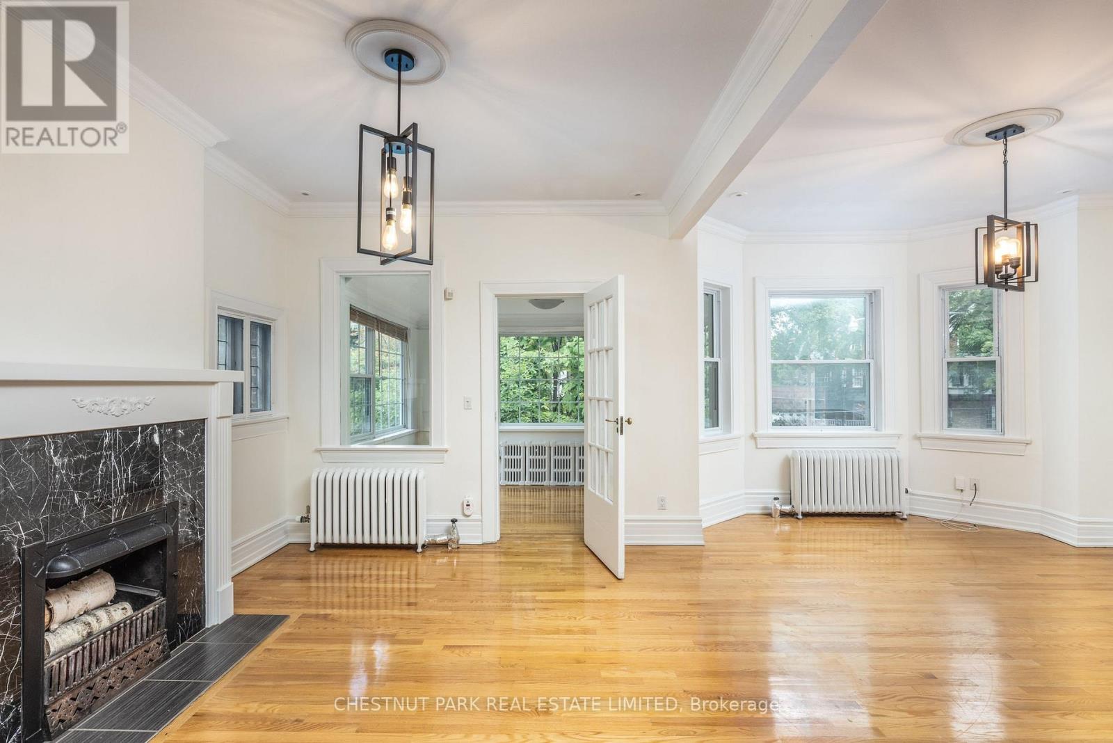A well-lit, spacious room with a fireplace and wooden floors.
