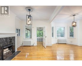 A well-lit, spacious room with a fireplace and wooden floors.