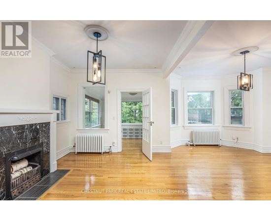 A well-lit, spacious room with a fireplace and wooden floors.