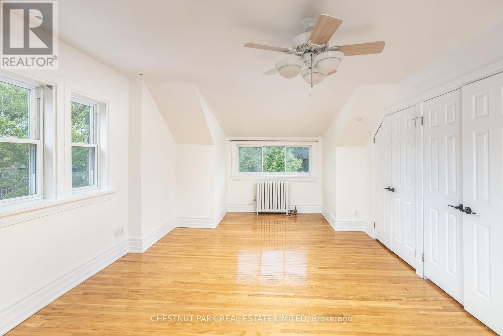 A room with a ceiling fan and wooden floors.