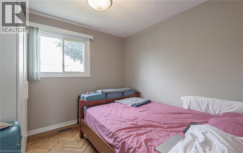 A bedroom with a pink bedspread and a window with a view of trees.