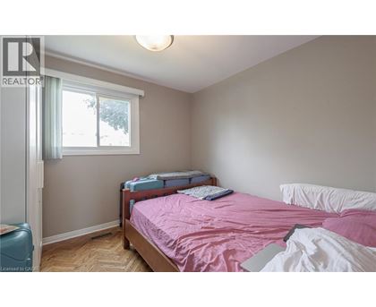 A bedroom with a pink bedspread and a window with a view of trees.