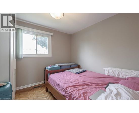 A bedroom with a pink bedspread and a window with a view of trees.