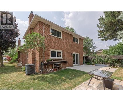 A house with a red brick exterior and a patio with a table and chairs.