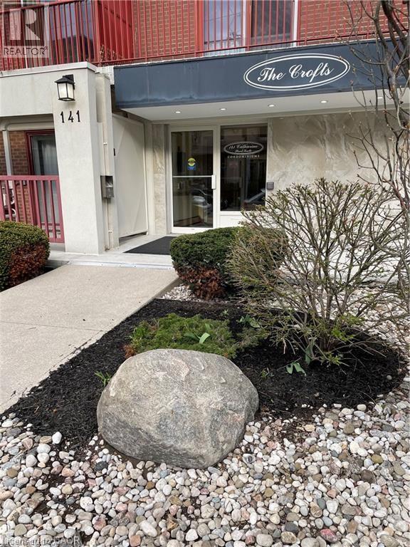 A large rock sits in the middle of a gravel area in front of a building.