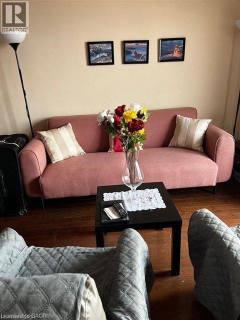 A living room with a pink couch, a coffee table with a vase of flowers, and a lamp.