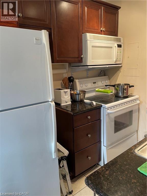 A white refrigerator is in a kitchen with a black counter top.