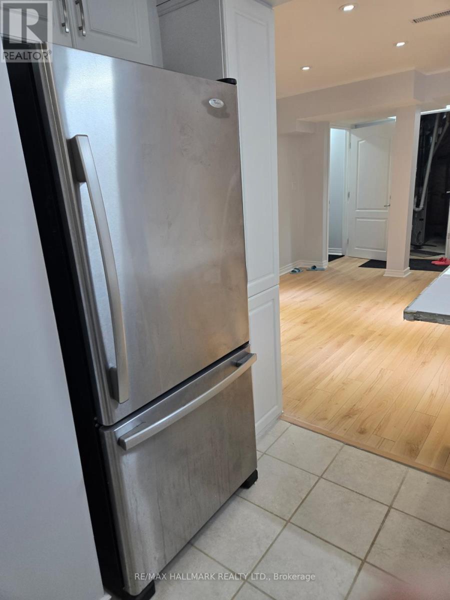 A stainless steel refrigerator in a kitchen with wooden flooring.
