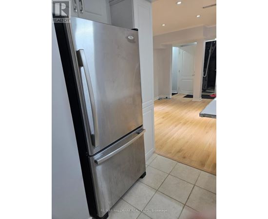 A stainless steel refrigerator in a kitchen with wooden flooring.