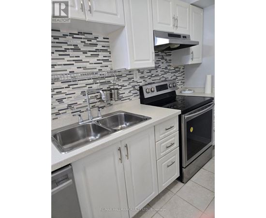 A kitchen with a black oven and a sink with two faucets.