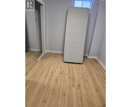 A white mattress is leaning against a wall in a room with wooden flooring.