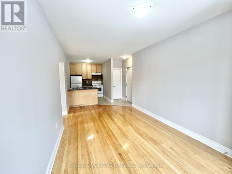 A spacious room with wooden flooring and white walls.