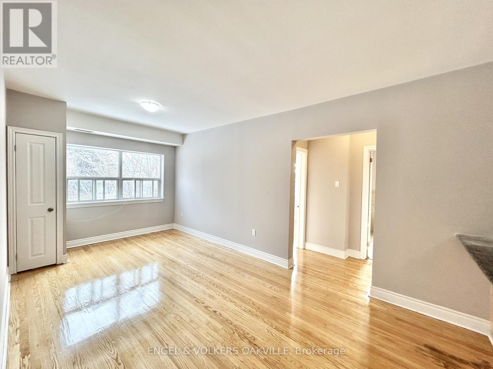 A spacious room with wooden flooring and white walls.