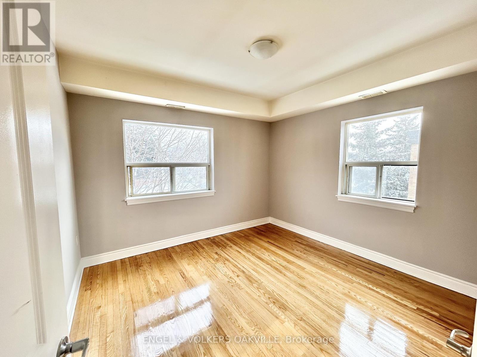 A room with wooden floors and two windows.