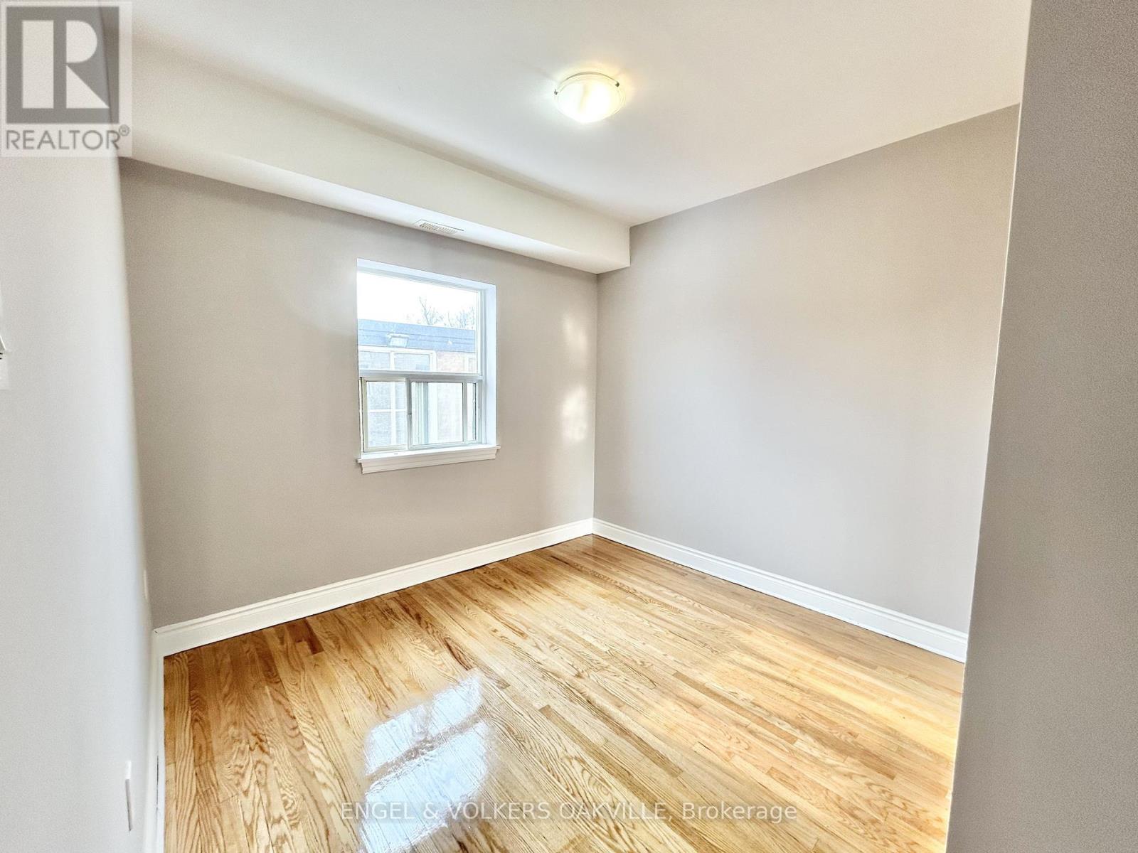 Empty room with wooden flooring and a window.