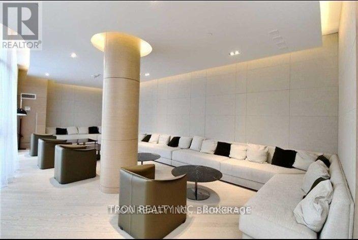 A modern living room with a long white couch and a tall column in the middle.