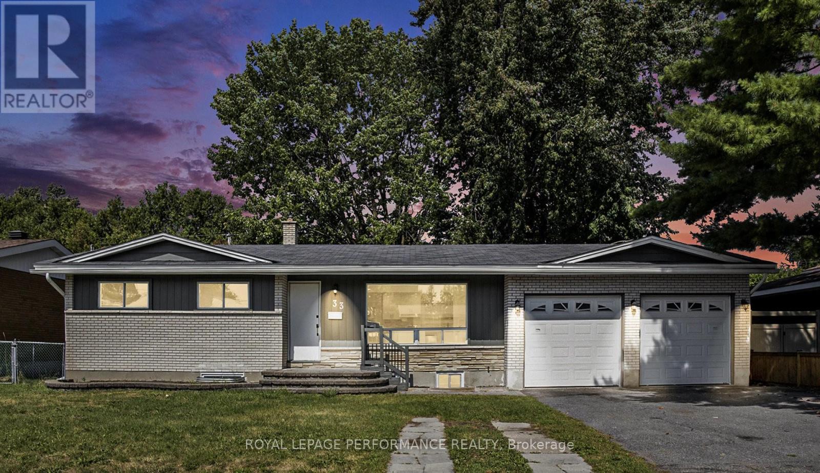 A house with a garage and a tree in front of it.
