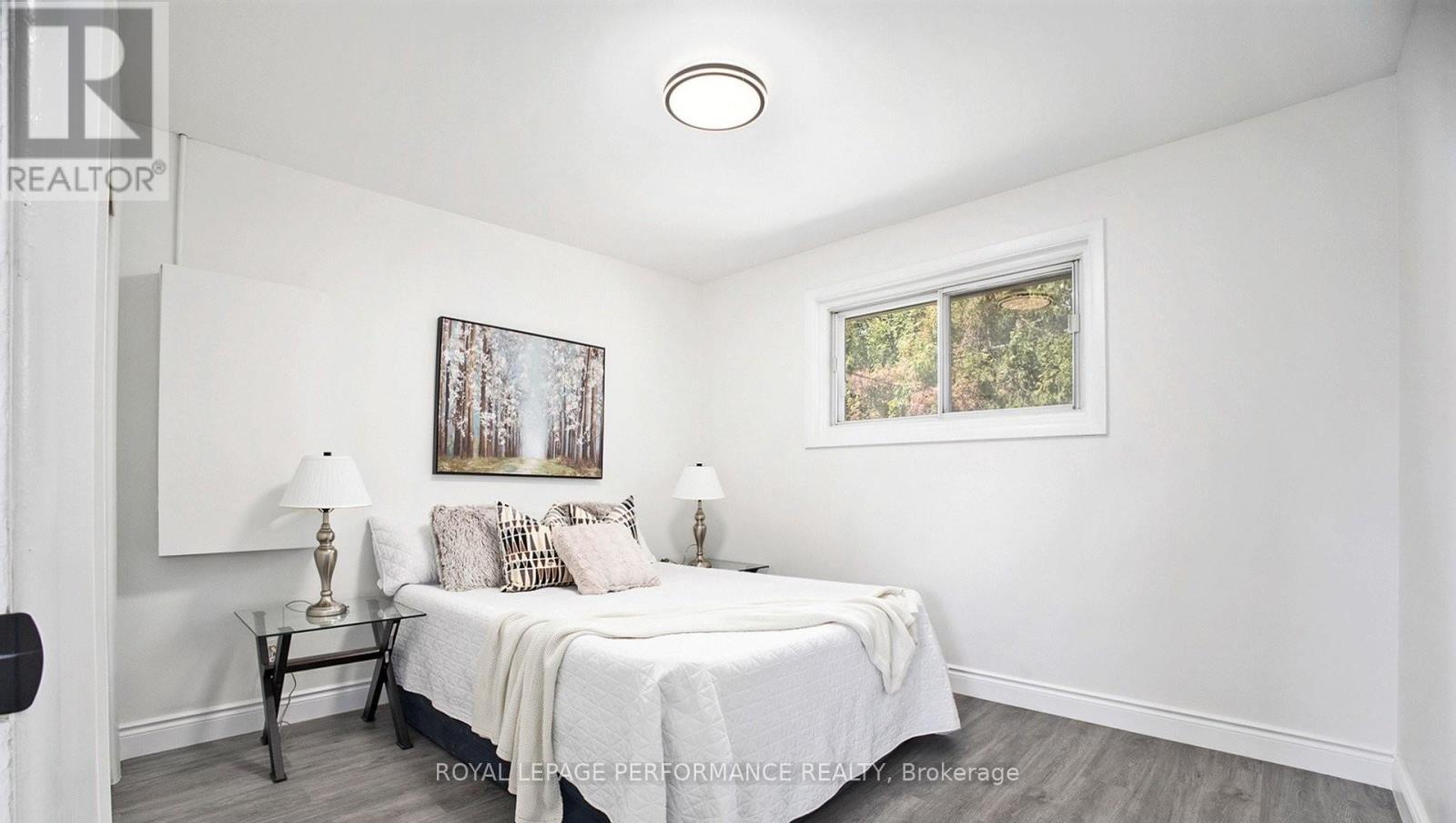 A bedroom with a bed, nightstands, and a painting on the wall.