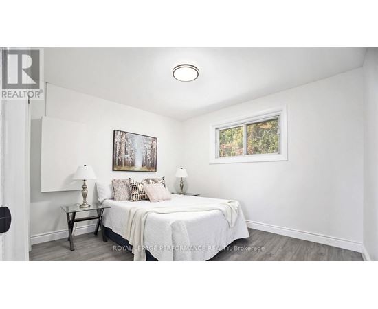 A bedroom with a bed, nightstands, and a painting on the wall.