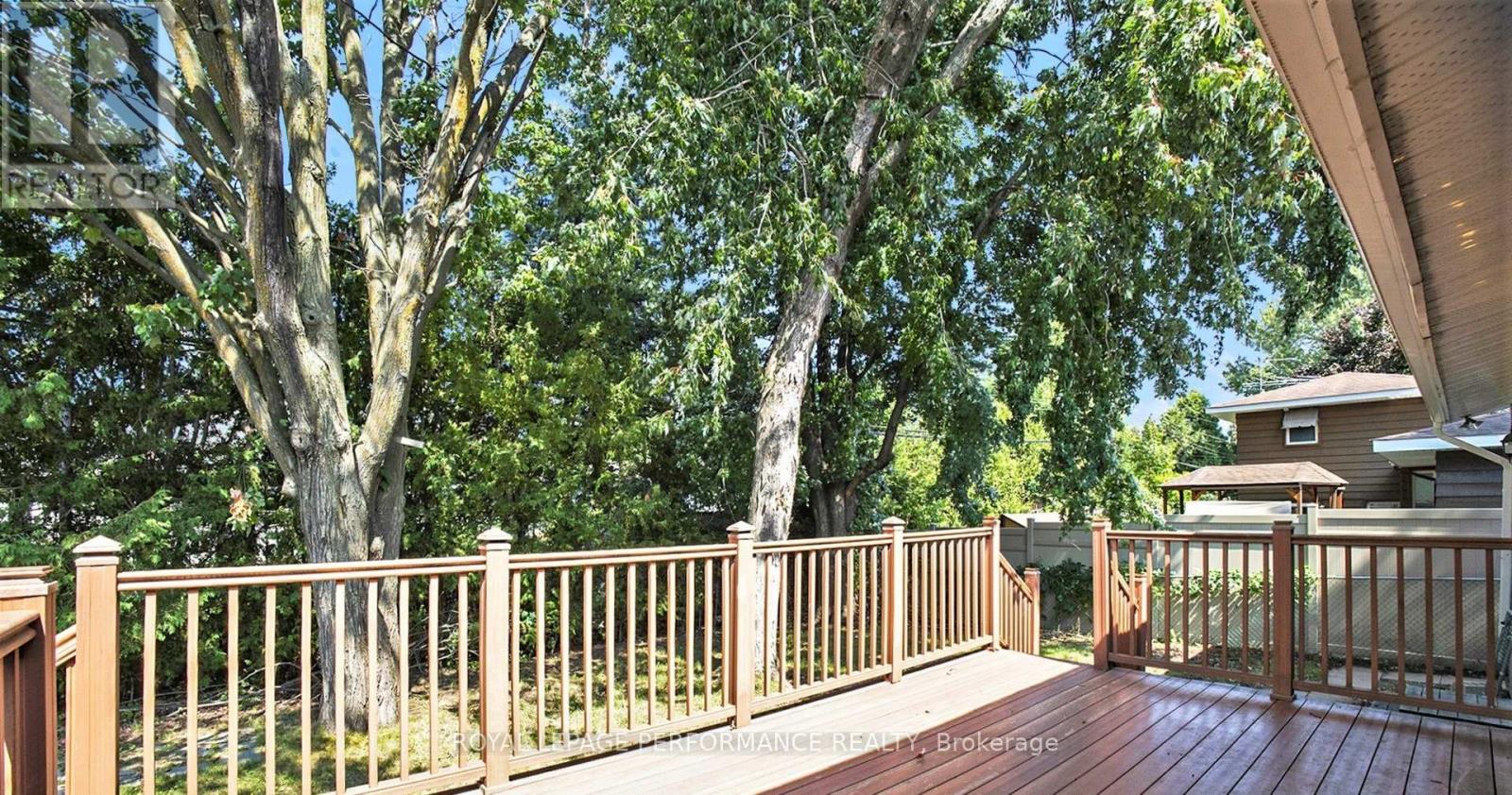 A wooden deck with a railing and trees in the background.