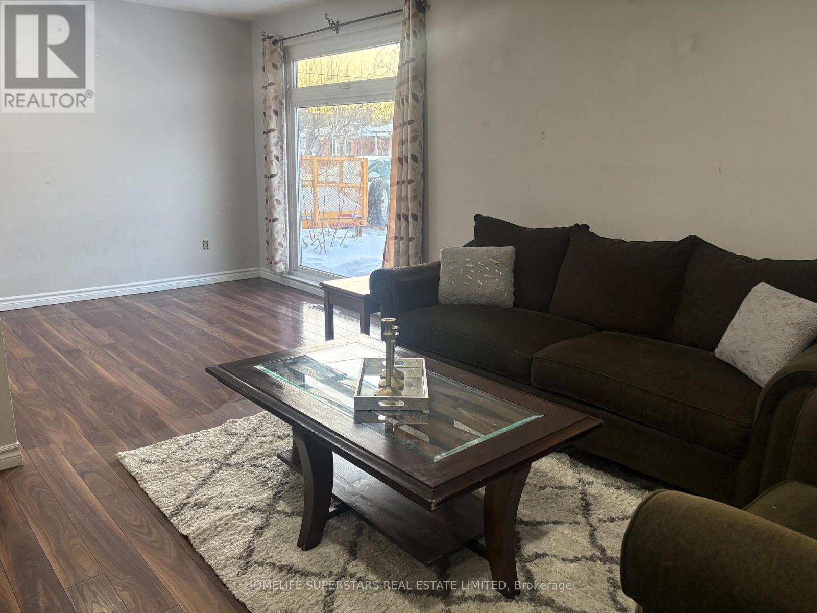 A living room with a brown couch and a glass coffee table.