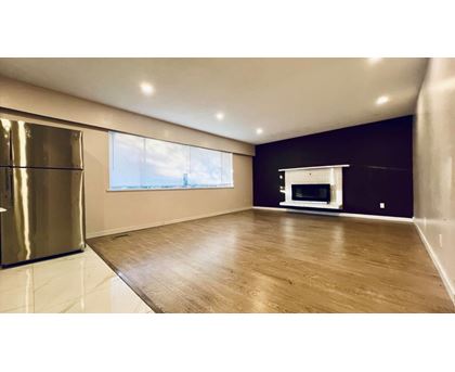A spacious room with wooden flooring and a large window.