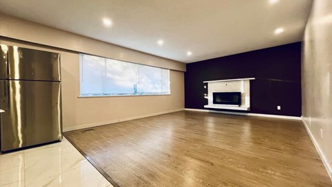 A spacious room with wooden flooring and a large window.