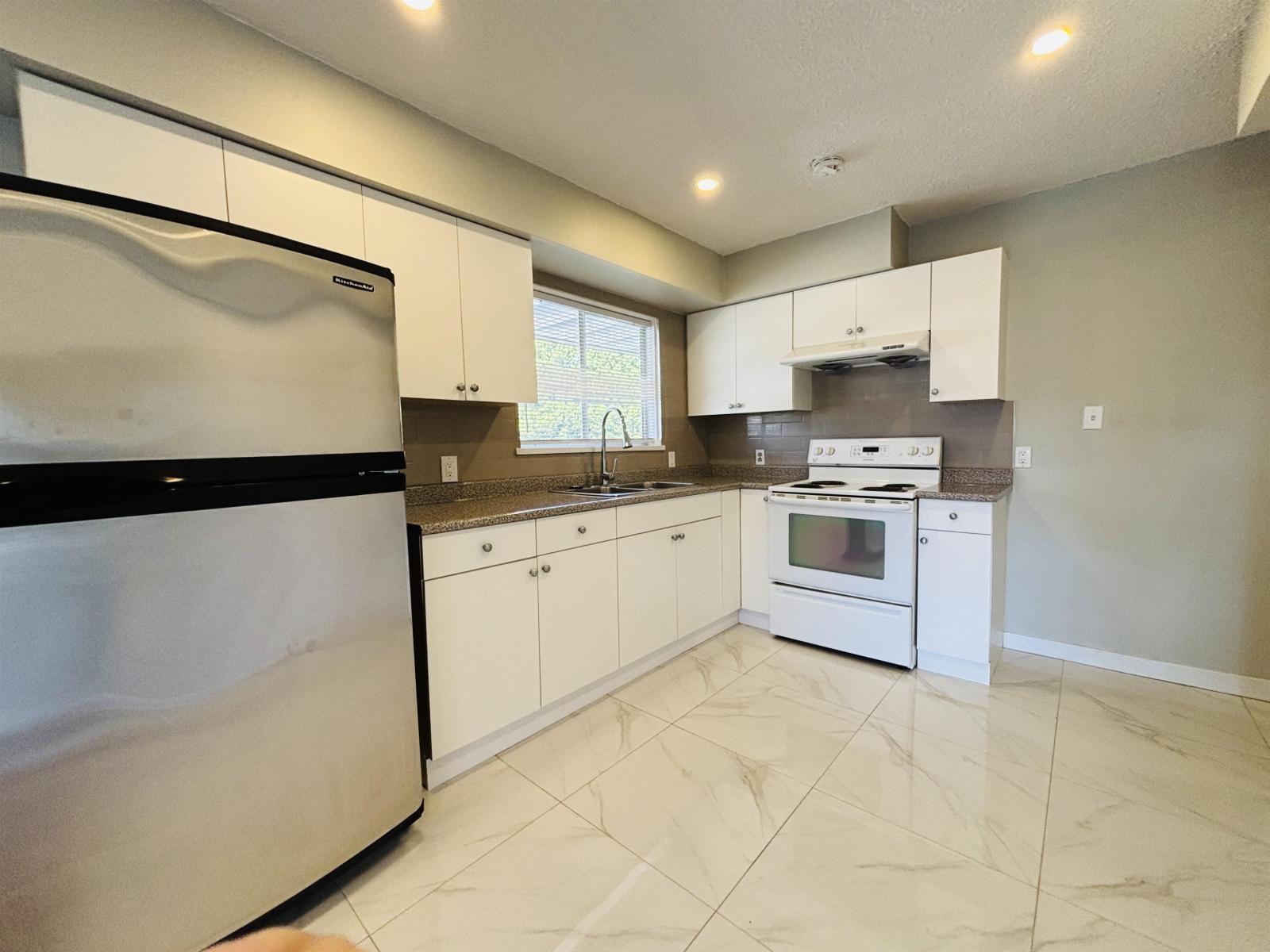 A kitchen with white cabinets and a black fridge.