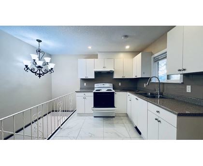 A kitchen with white cabinets and a black fridge.