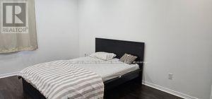 A bedroom with a bed and a Realtor sign on the wall.