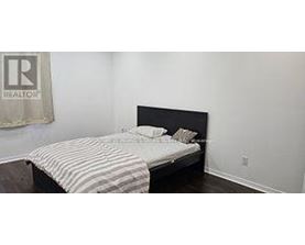 A bedroom with a bed and a Realtor sign on the wall.