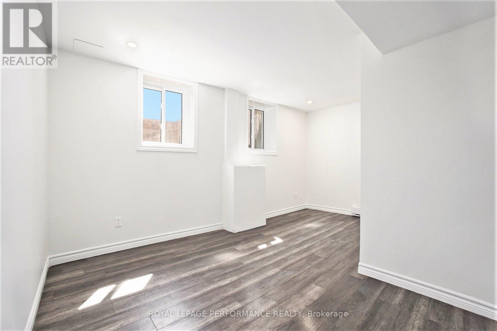 A white room with wooden flooring and a window.
