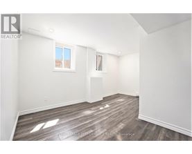 A white room with wooden flooring and a window.