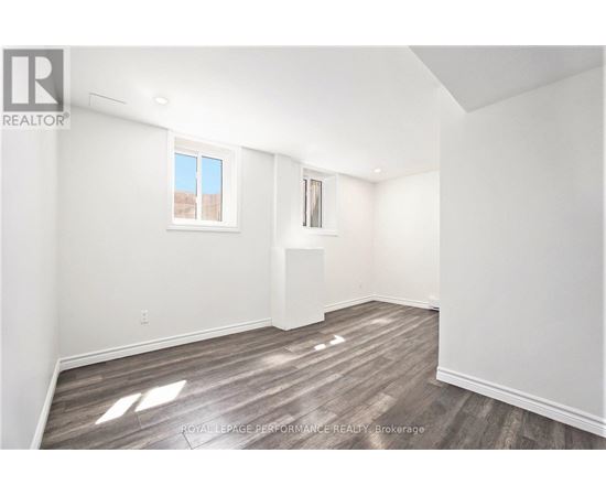 A white room with wooden flooring and a window.