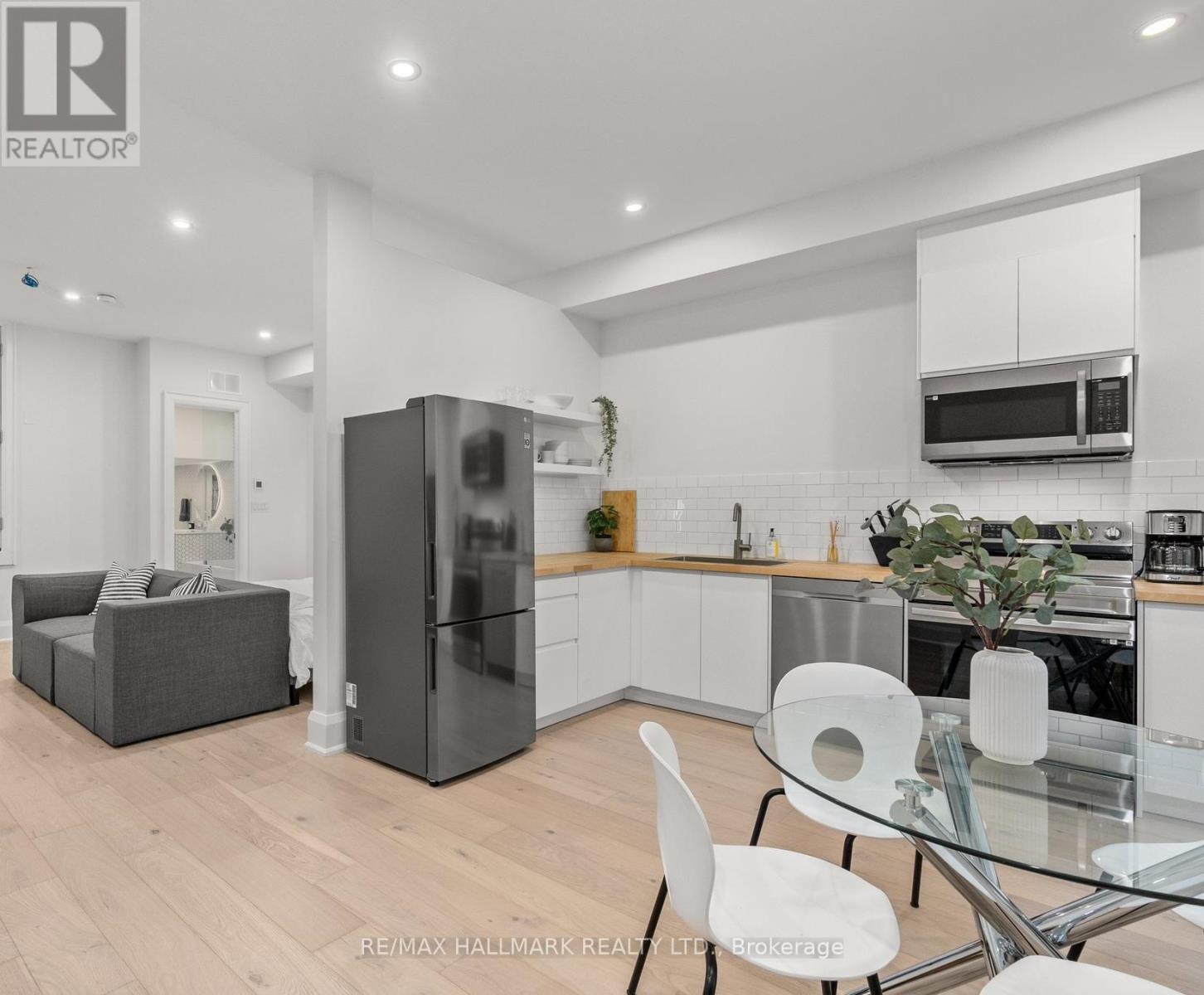A modern kitchen with a glass table and white chairs.