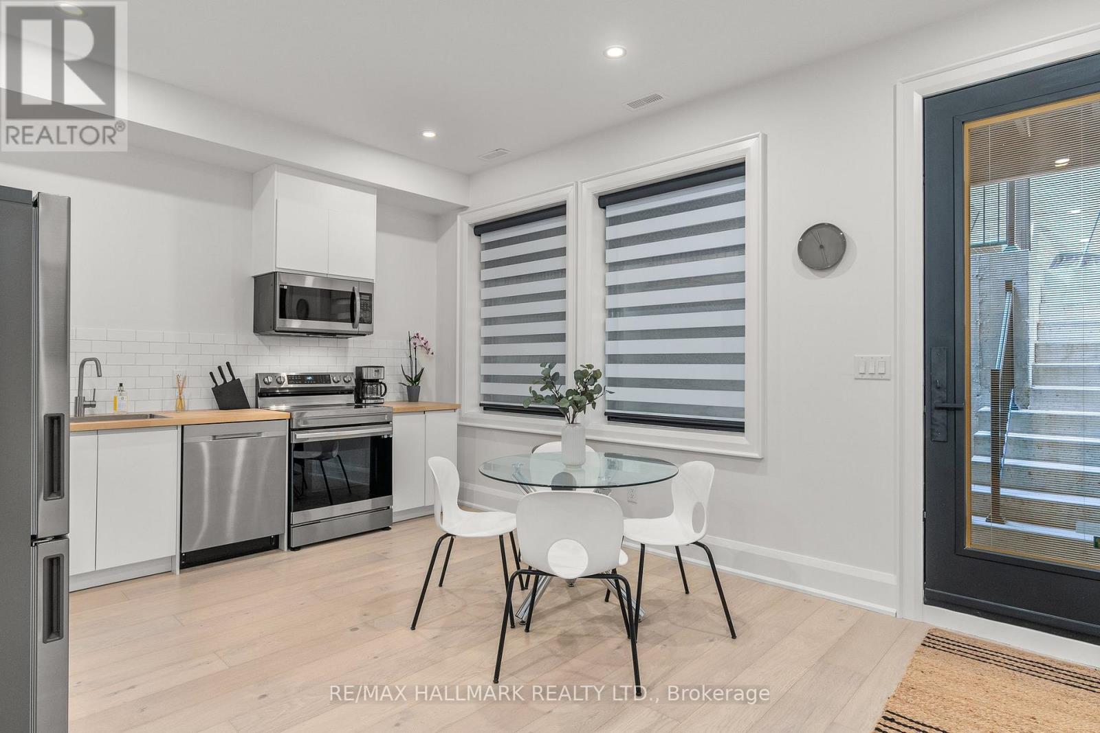 A modern kitchen with white chairs and a glass table.