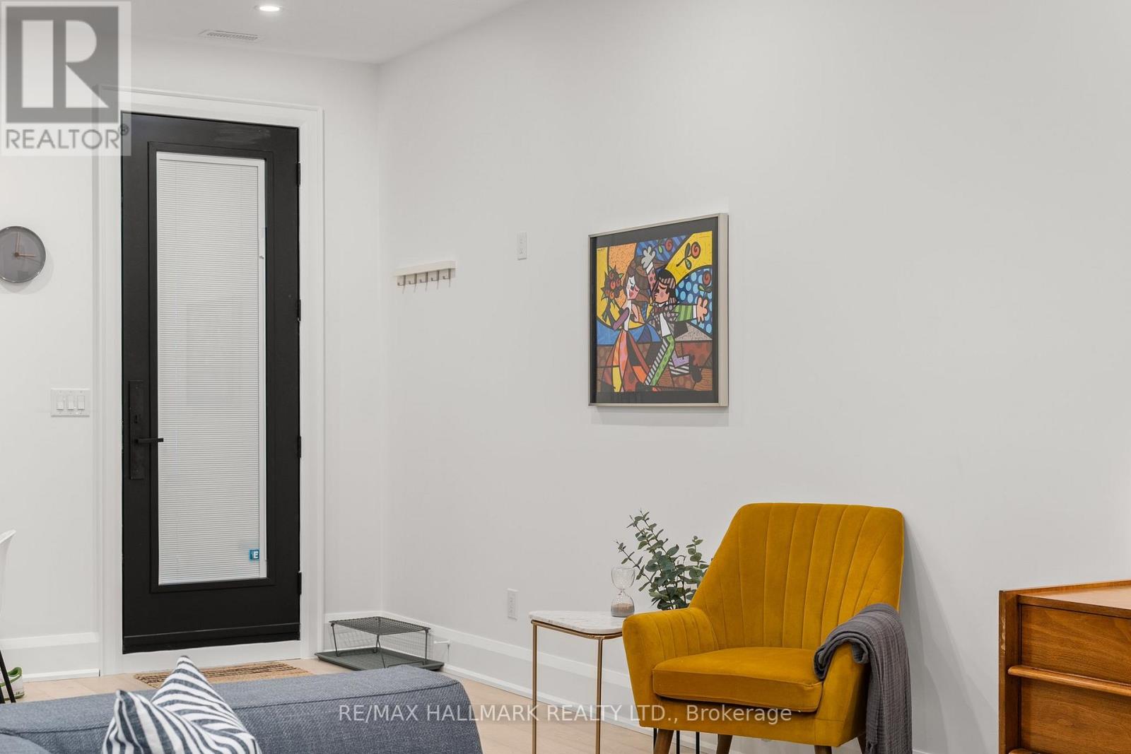 A bedroom with a yellow chair and a picture on the wall.