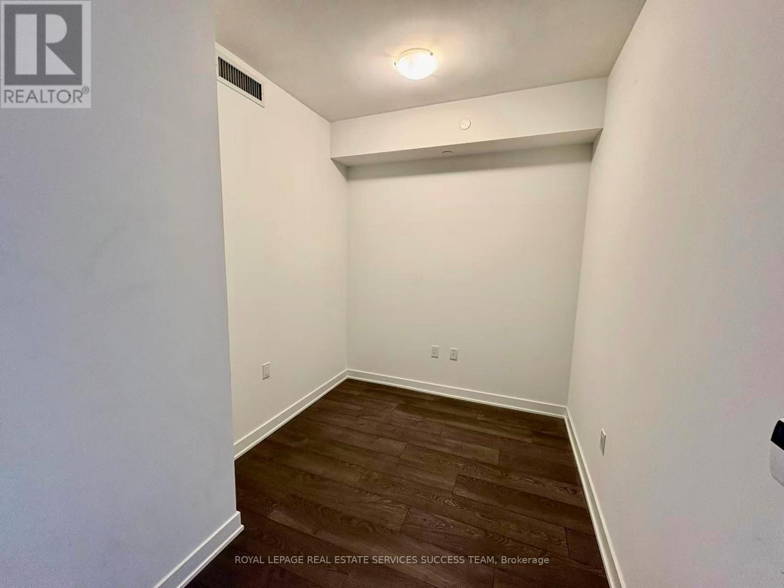 A room with wooden flooring and white walls.