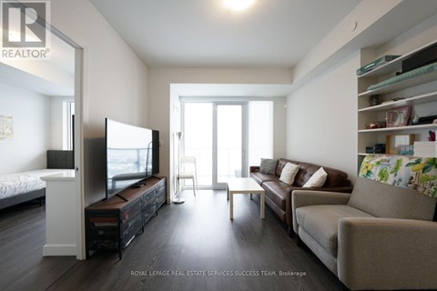 A living room with a brown couch, a television, and a window.