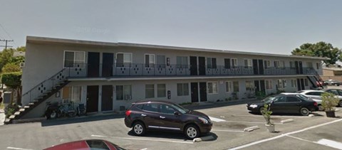 A building with a balcony and a car parked in front.