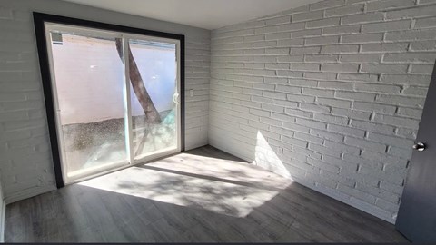 A room with a white brick wall and a sliding glass door.