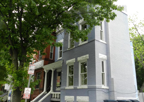 A blue and white two story building with a tree in front.