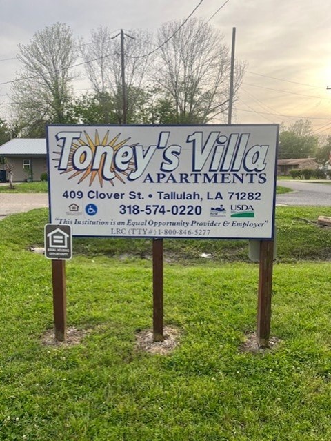 A sign for Toney's Villa Apartments is displayed in front of a house.