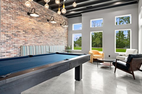 A pool table is in the middle of a room with a brick wall and striped curtains.