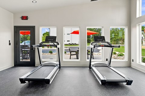 A gym with two treadmors and a red exit sign.