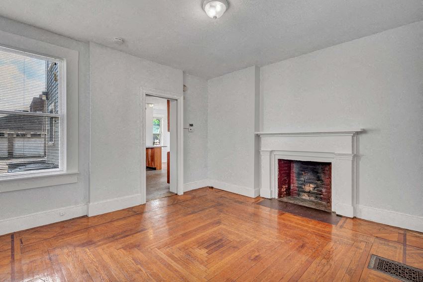 an empty living room with a fireplace and wooden floors