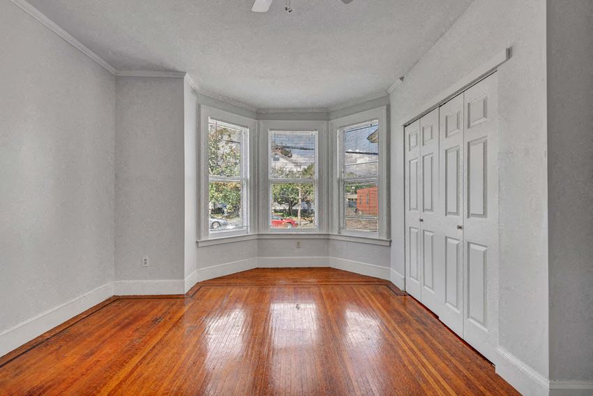 an empty living room with wood floors and a bay window