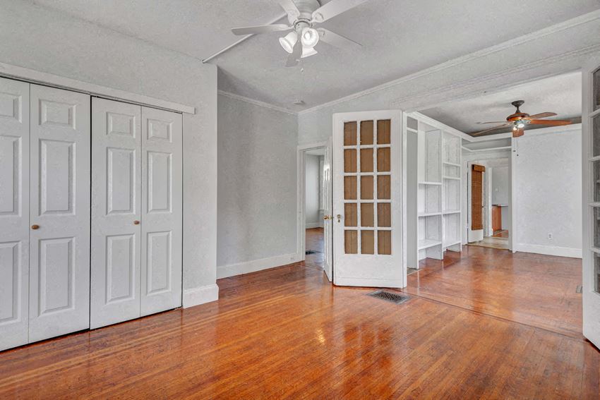 an empty living room with wood floors and a ceiling fan