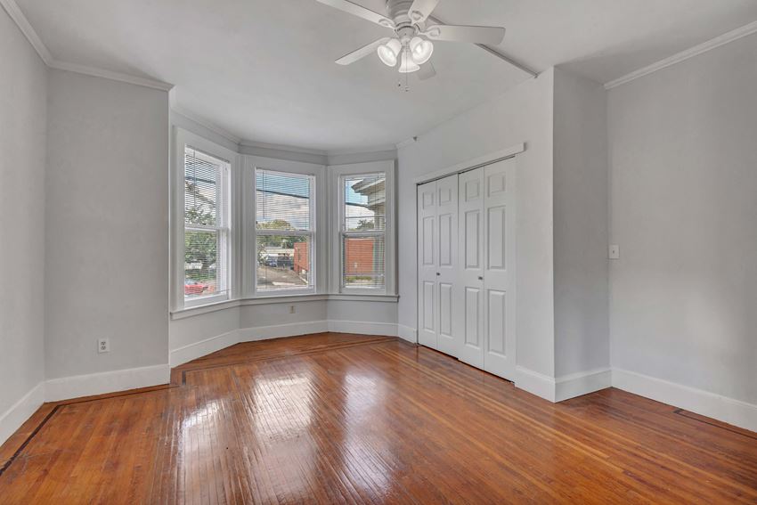 an empty living room with wood floors and a ceiling fan